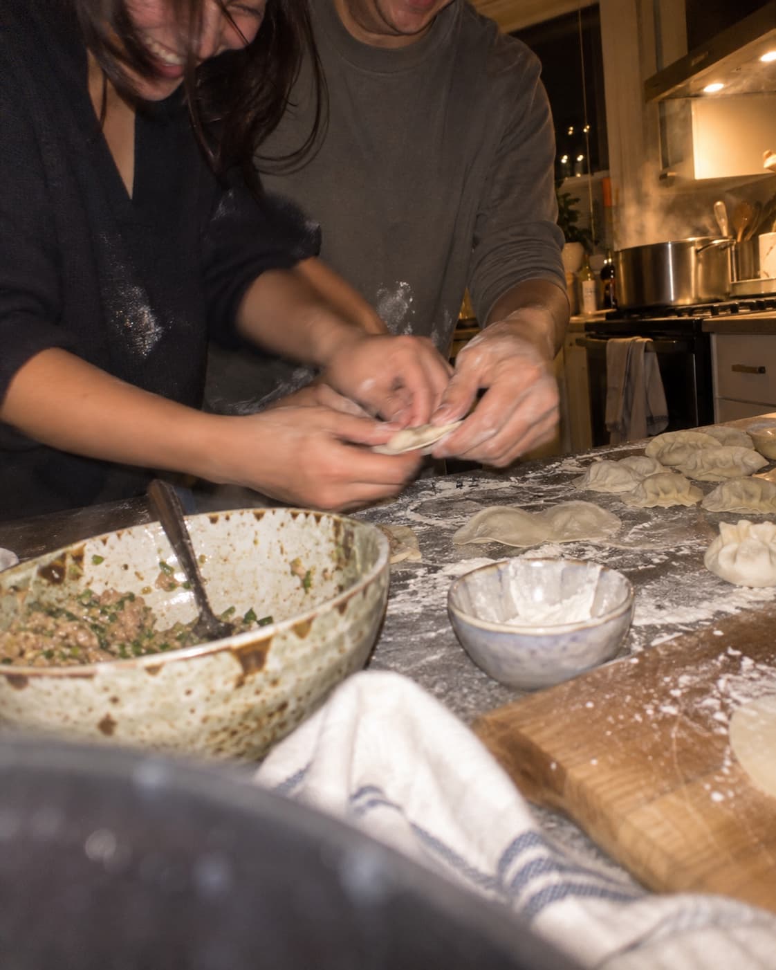 Two pairs of hands working dough in bowls on a kitchen counter