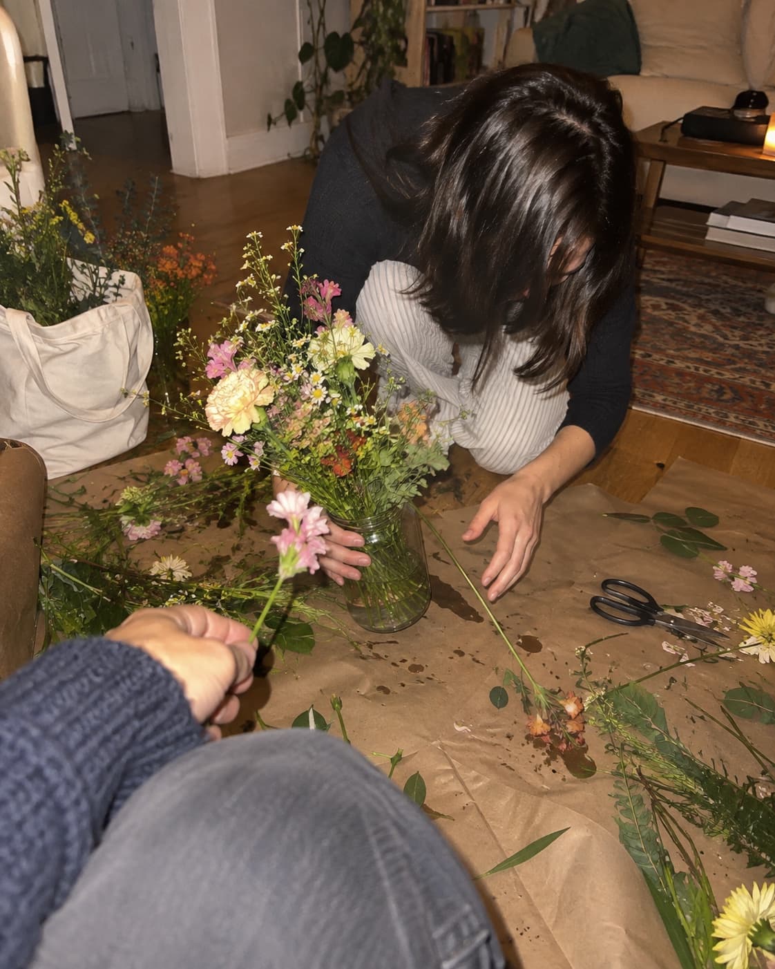 Two people arranging dried flowers on the floor