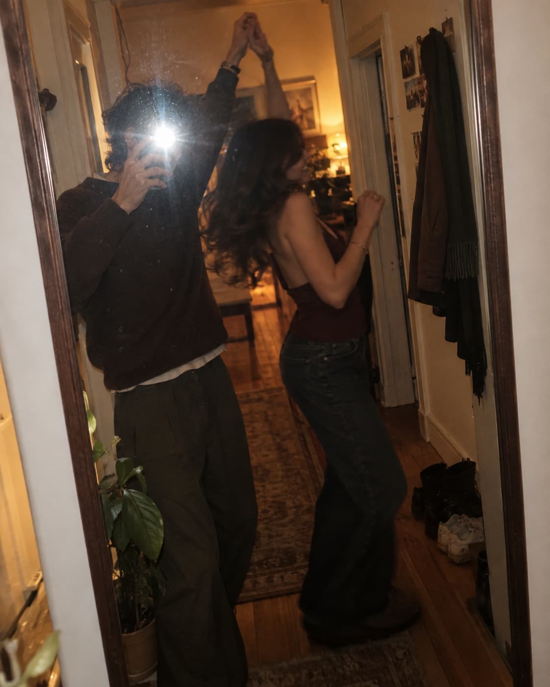 A couple photographing themselves in a hallway mirror with a flash