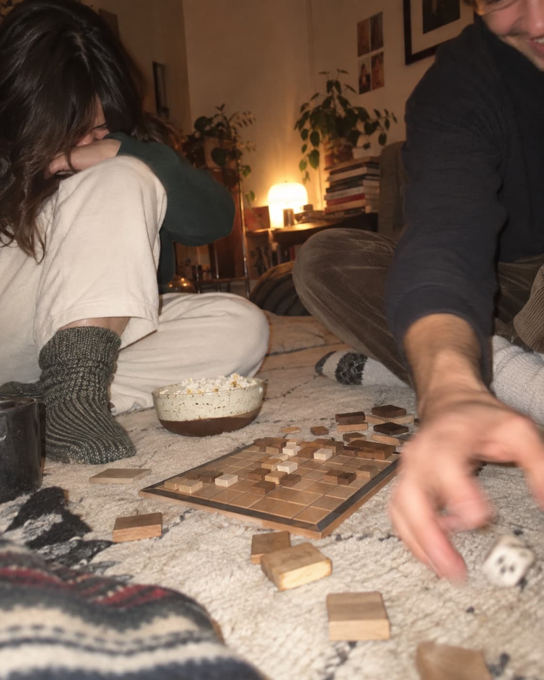 A wooden tile game laid out on a rug, snacks and a lamp nearby